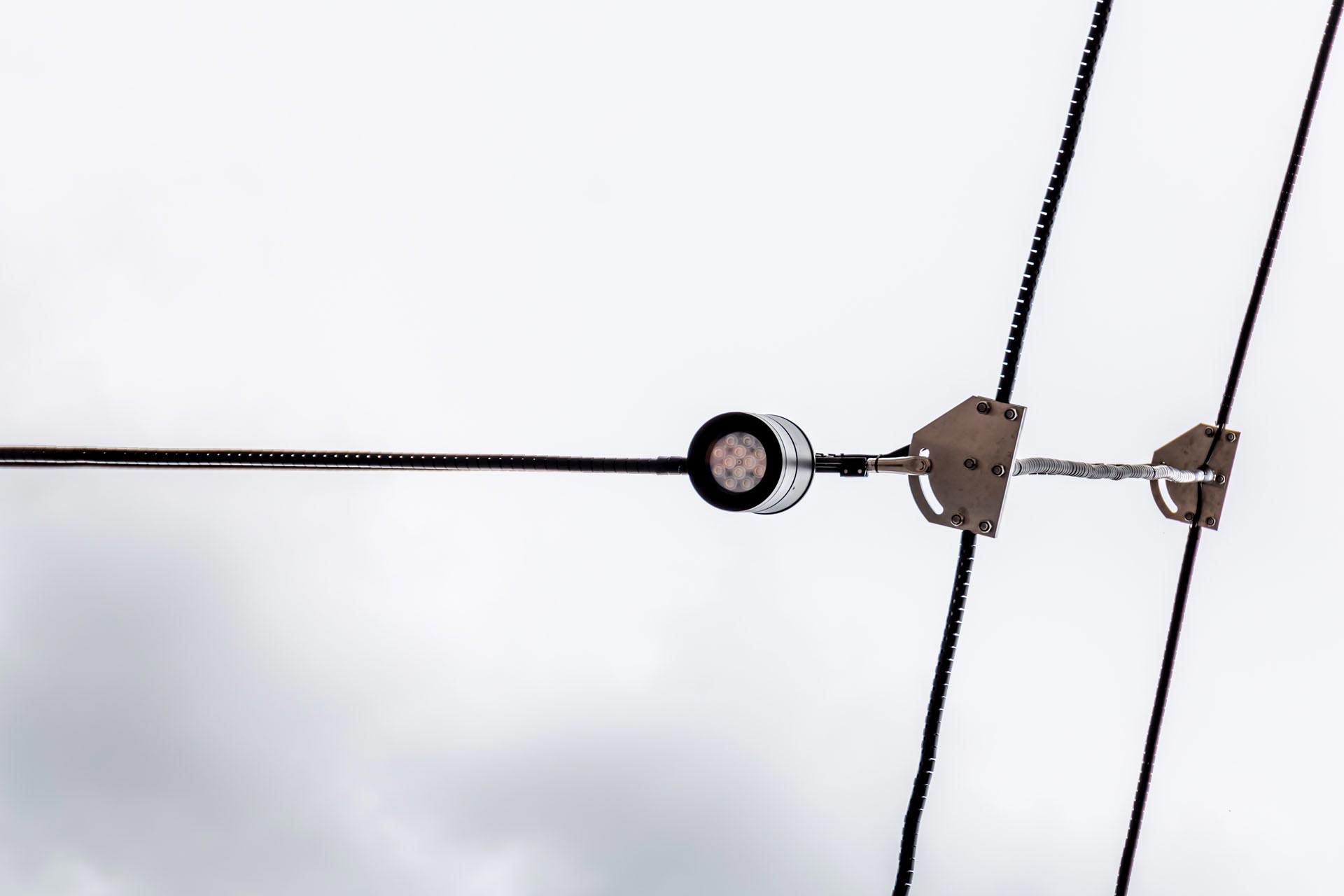 Detail of a LED lamp hanging on a cable suspension by Jakob