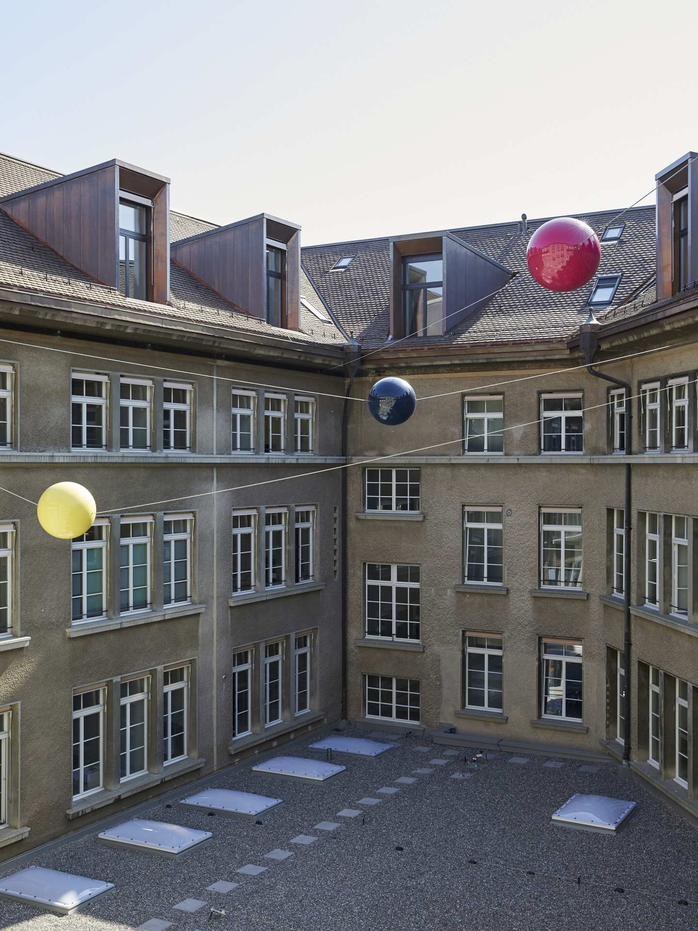 View of the courtyard with yellow, blue and red plastic balls on steel cables