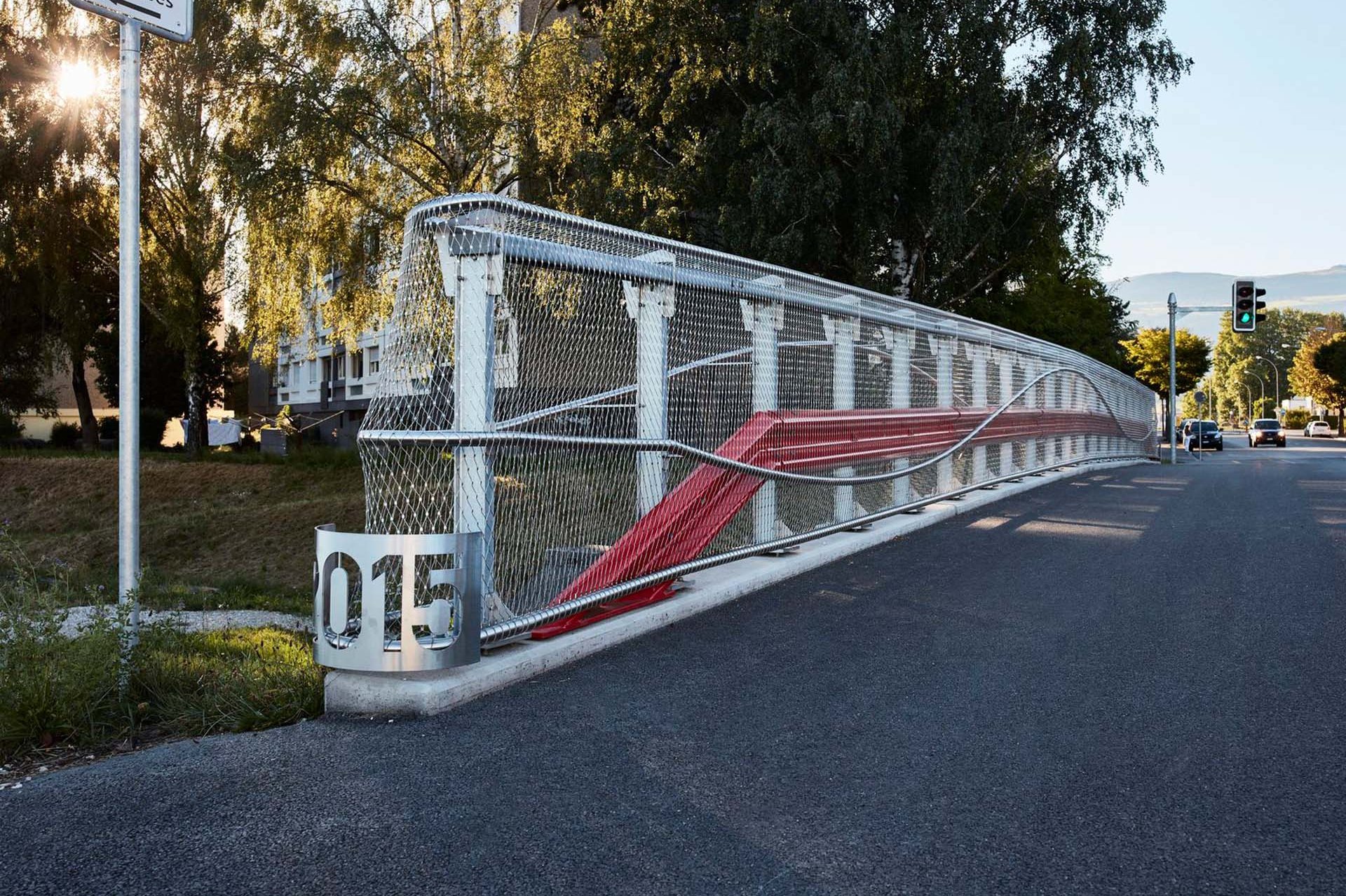 Webnet covers the railings on both sides of the bridge. It serves not only as a railing infill, but lets the striking red crash barriers and the curved steel railings shine.