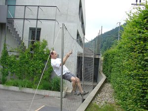 Ein Mann versucht auf einen Webnet-Zaun zu klettern